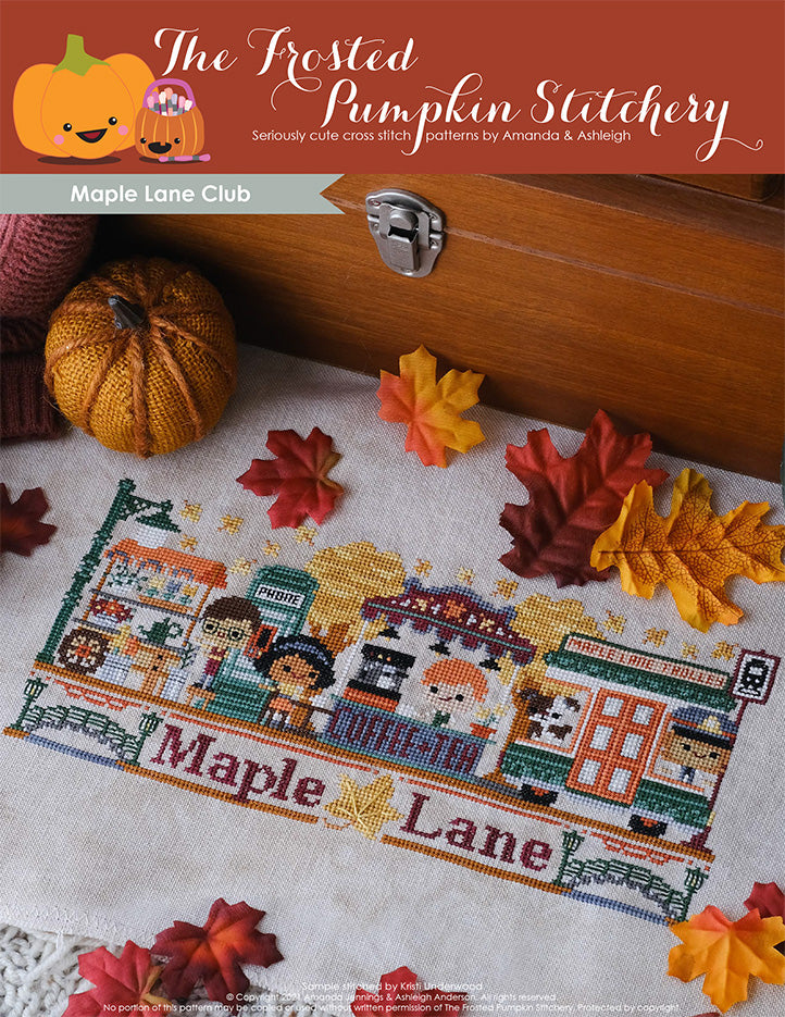 Maple Lane Cross Stitch Pattern. Cover image includes a barista working at the Coffee & Tea Bar, phone booth, a customer sitting at a table with her drink, the Maple Lane Trolley and a flower cart. They are surrounded by maple trees and floating maple leaves.