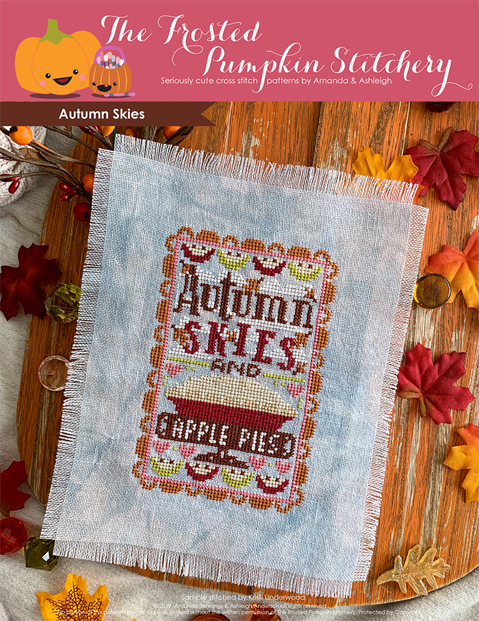 Autumn Skies counted cross stitch pattern. Text reads Autumn Skies and Apple Pies. Image of blue linen with the pattern cross stitched onto it, a big apple pie in the center, pie slices on the borders.