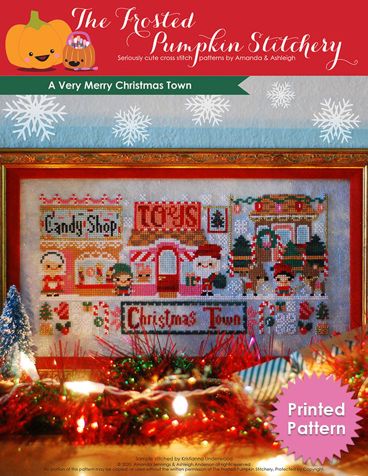 A Very Merry Christmas Town counted cross stitch pattern with a candy shop, Mrs. Claus, toy shop, Santa, reindeer and a Christmas tree lot.