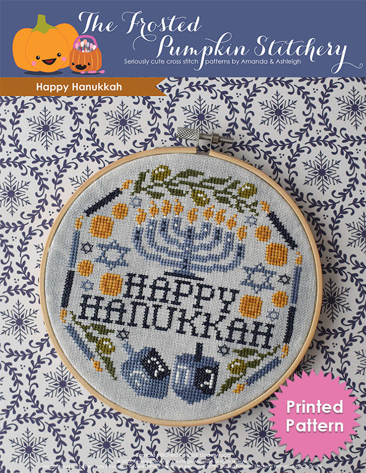 Happy Hanukkah counted cross stitch pattern. Image of a menorah surrounded by the words "Happy Hanukkah," candles, multiple Star of David, gelt, dreidels and olive branches. Printed Pattern.