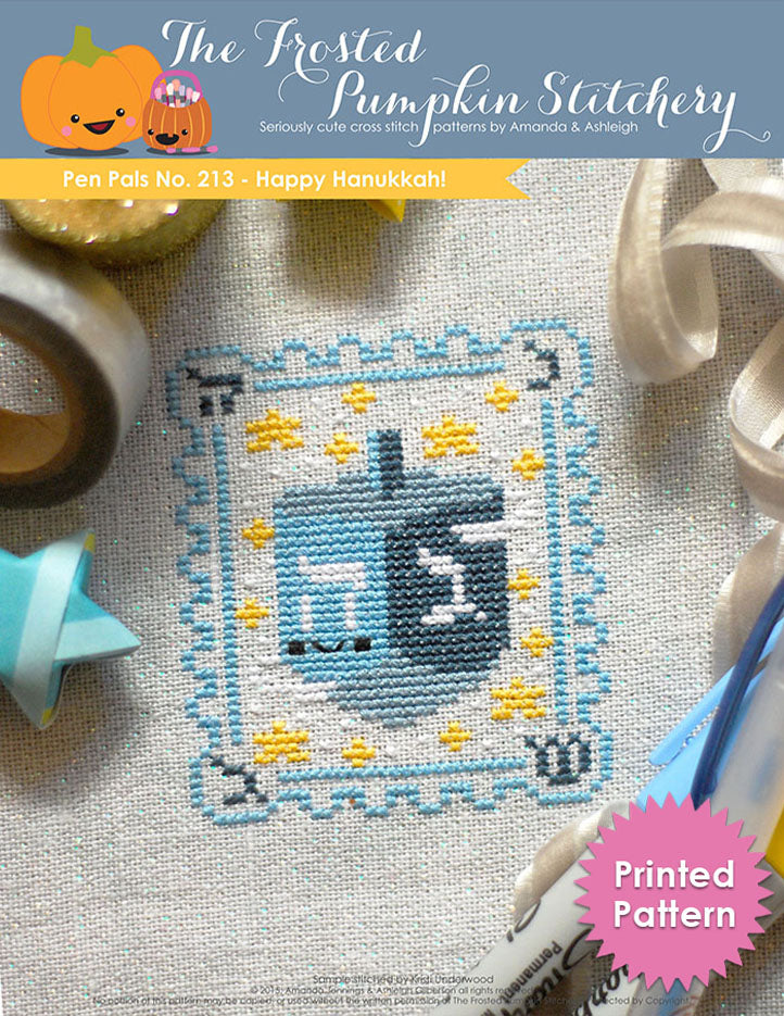 Pen Pals No 213 Happy Hannukah counted cross stitch pattern. A blue dreidel with a kawaii face surrounded by stars.