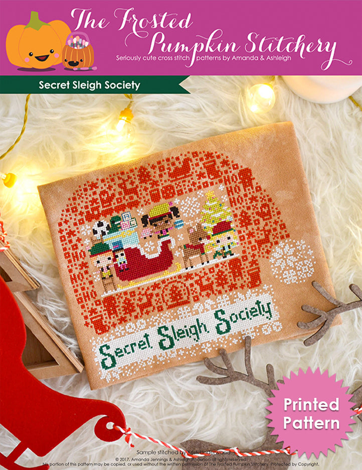 Secret Sleigh Society counted cross stitch pattern. Three elves surround Santa's sleigh with the text below "Secret Sleigh Society". Printed Pattern.