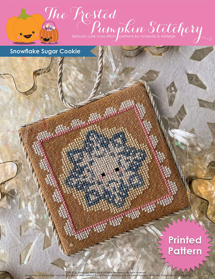 Image of Snowflake Sugar Cookie Cross Stitch Pattern. This pattern features a snowflake shaped sugar cookie, surrounded by a pink and white frosting frame. Printed Pattern.