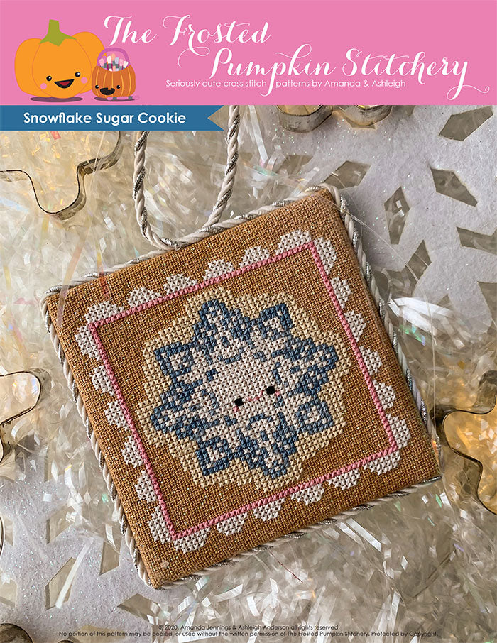 Image of Snowflake Sugar Cookie Cross Stitch Pattern. This pattern features a  snowflake shaped sugar cookie, surrounded by a pink and white frosting frame. 