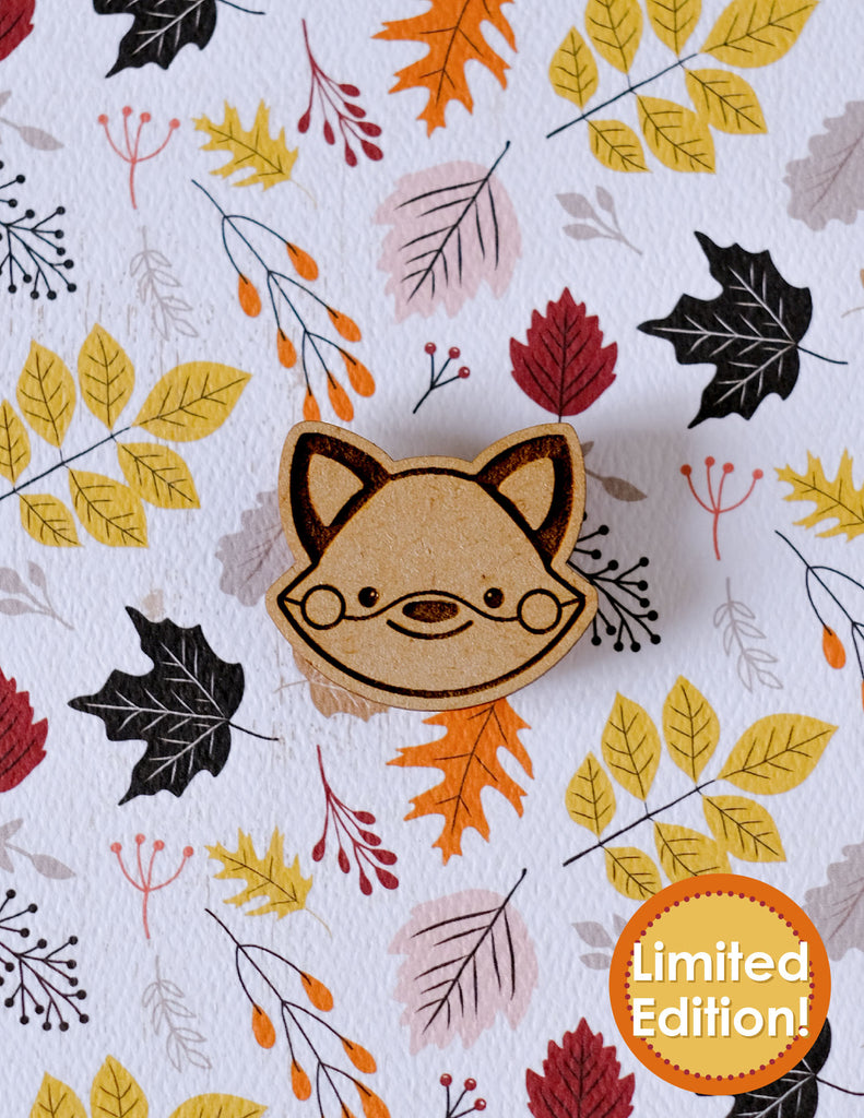Wooden fox-shaped needleminder on a  autumn leaf paper background .