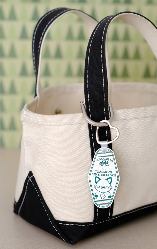 a green and white key tag attached to a tote strap
