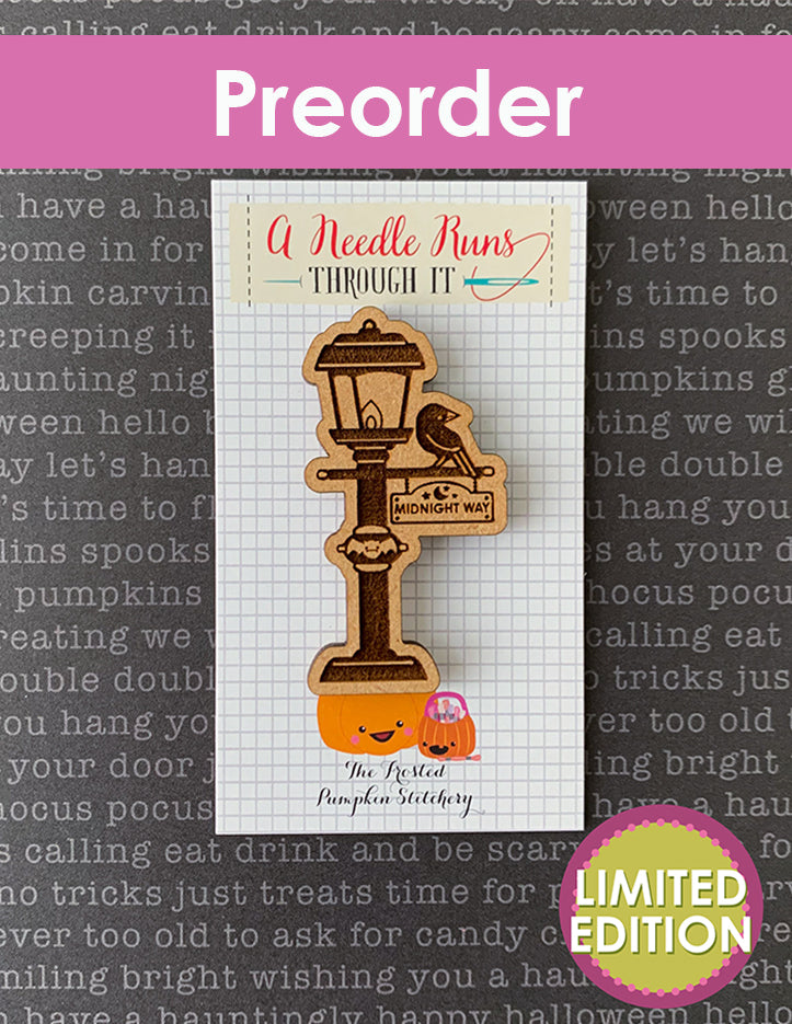 Wooden Halloween needleminder with a lantern design with a crow against a patterned background.