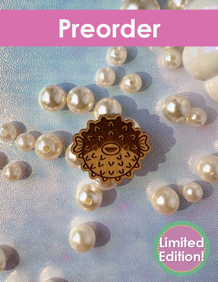Wooden pufferfish ornament with pearls on a textured background, preorder limited edition text.
