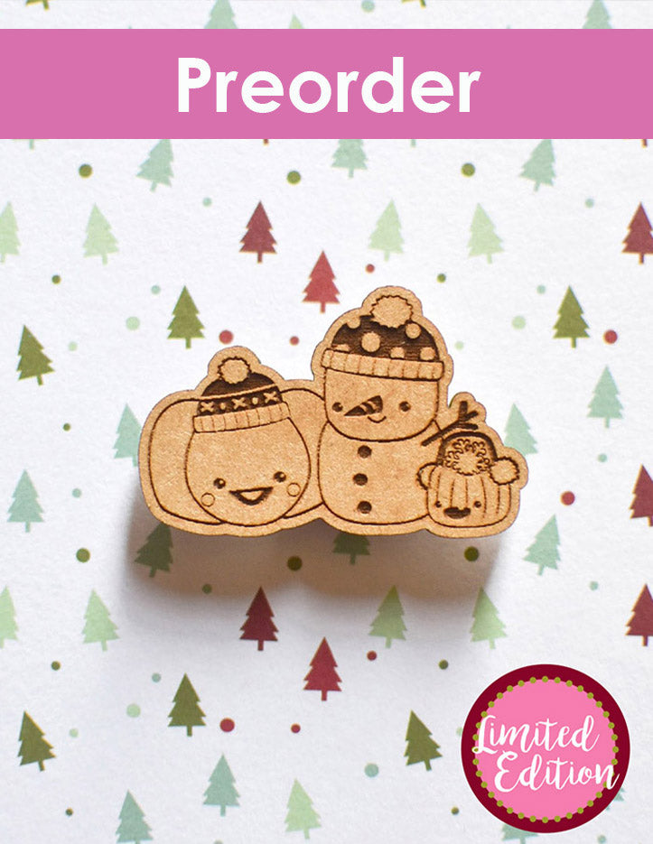 Wooden snowman with two pumpkins needleminder with a pre-order label on a festive background with trees and dots.