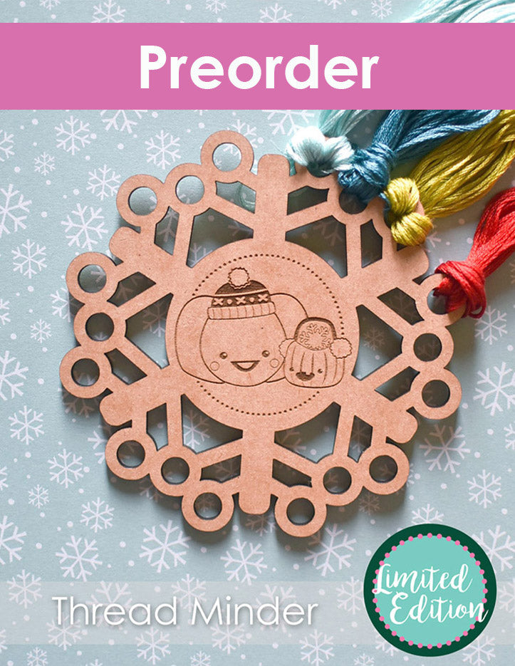 Wooden snowflake thread minder on a light blue background with snowflakes, accompanied by colorful threads.