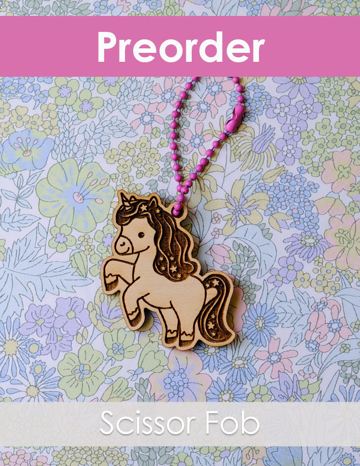 Scissor fob with unicorn design on a floral patterned background
