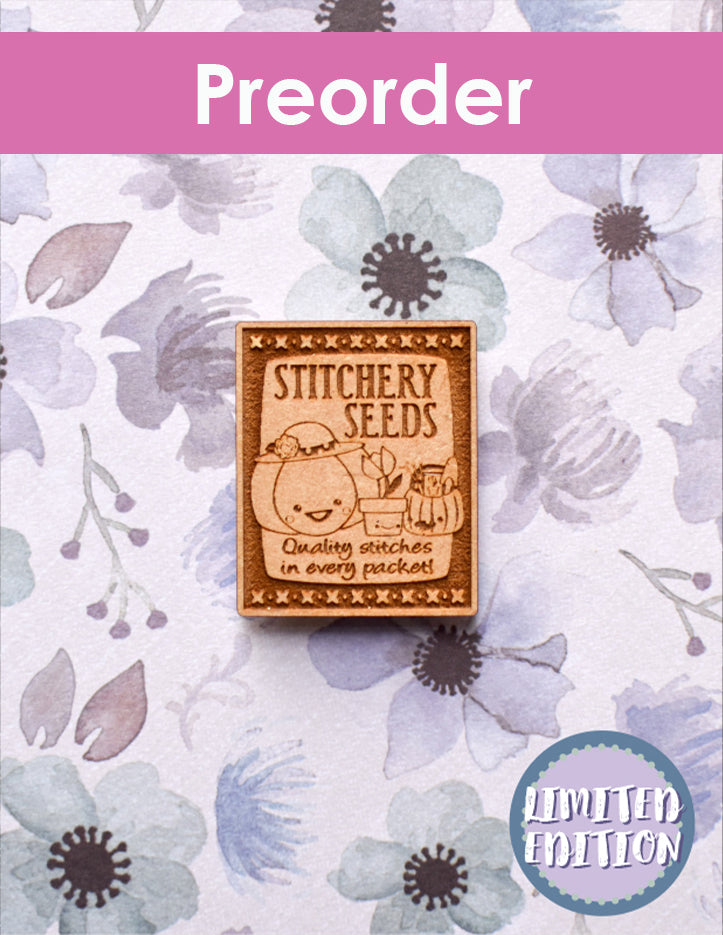 Stitchery Seeds needleminder with floral design and preorder text on a purple background