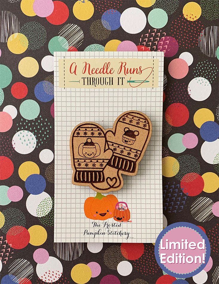 Image of a wooden needleminder with Sugarloaf and Jack (TFPS mascots who are pumpkins.) Each pumpkin is on a winter mitten.  