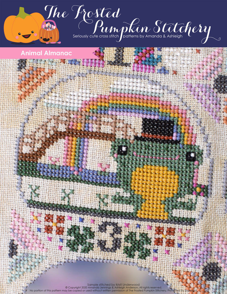 Animal Almanac Cross Stitch Pattern Cover. Image of a frog who is wearing a top hat in front of a bridge with a rainbow.