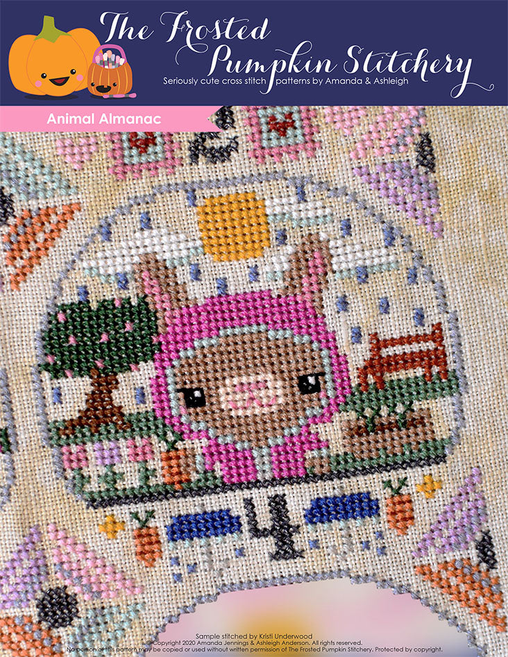 Animal Almanac Cross Stitch Pattern Cover. Image of a bunny in a raincoat holding a carrot. It is raining, the sun is trying to come out and there are plants and a garden in the background.