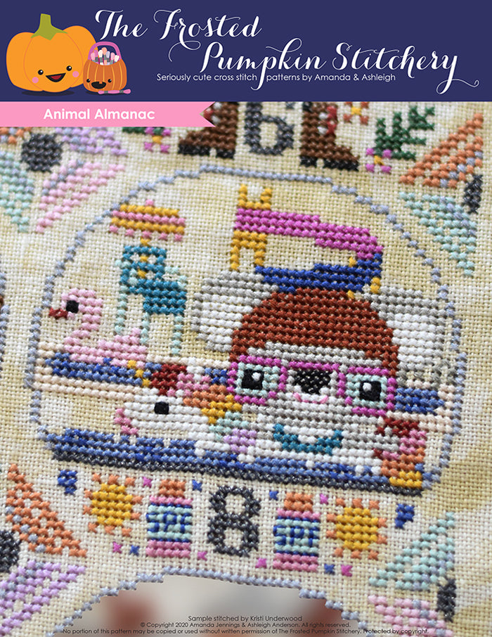Animal Almanac Cross Stitch Pattern Cover. Koala wearing swim cap, goggles and floating in pool at waterpark wearing a unicorn floaty. Lifeguard stand and swan floaty in background.