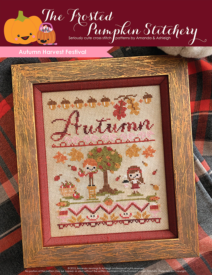 Autumn Harvest Festival fall counted cross stitch pattern. A white man with red hair and a white woman with brown hair in a burgundy headband are apple picking. He's standing on a ladder, she's holding a latte cup. The text is a hand written font that says Autumn in hand dyed thread. The border is acorns, apple slices and pie.