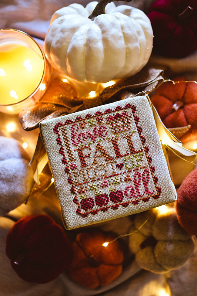 I love Fall counted cross stitch pattern. Text reads "I love fall most of all" in variegated embroidery floss with a basket of apples and surrounded by apples and felt pumpkins.
