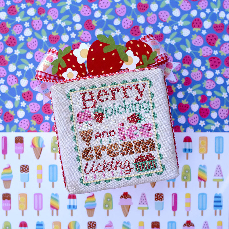 Berry Picking counted cross stitch pattern. Text reads "Berry Picking and Ice Cream Licking". The font looks like ice cream with sprinkles and waffle cone. Background of the image is half popsicles and half strawberries