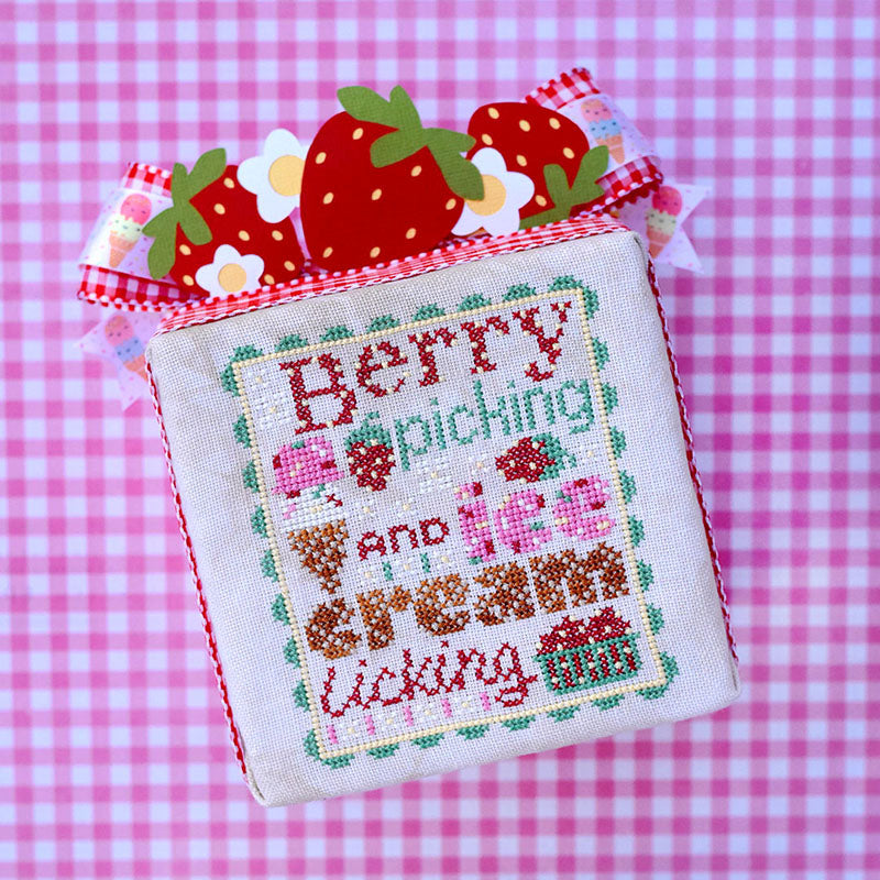 Berry Picking counted cross stitch pattern. Text reads "Berry Picking and Ice Cream Licking". The font looks like ice cream with sprinkles and waffle cone. Background is pink gingham.