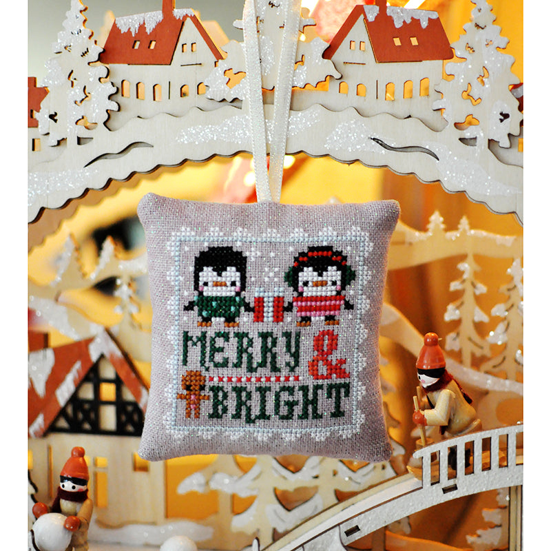 Penguin Merry and Bright Christmas ornament is hanging from a laser cut wooden scene.
