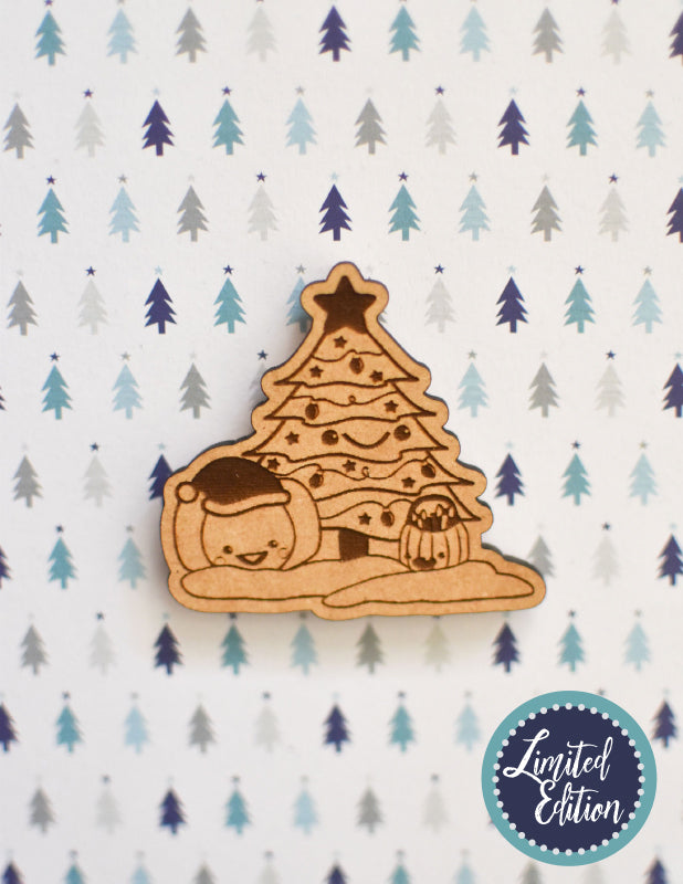 Image of a wooden needleminder with a Christmas tree and two pumpkins in the snow.