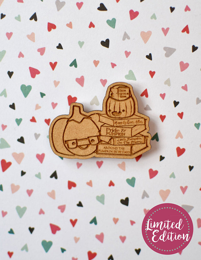 Image of a wooden needleminder with a stack of books and two pumpkins.