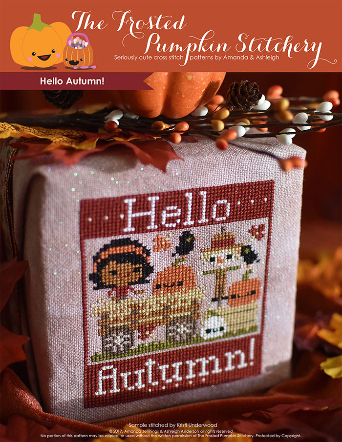 Hello Autumn counted cross stitch pattern. Brown skinned girl is on a hay ride with pumpkins and a scarecrow. 