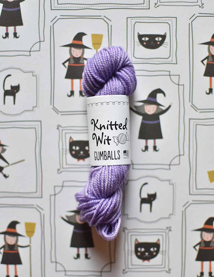 Knitted Wit Gumball Yarn. A mini skein of purple yarn with a label that reads "Knitted Wit Gumballs".