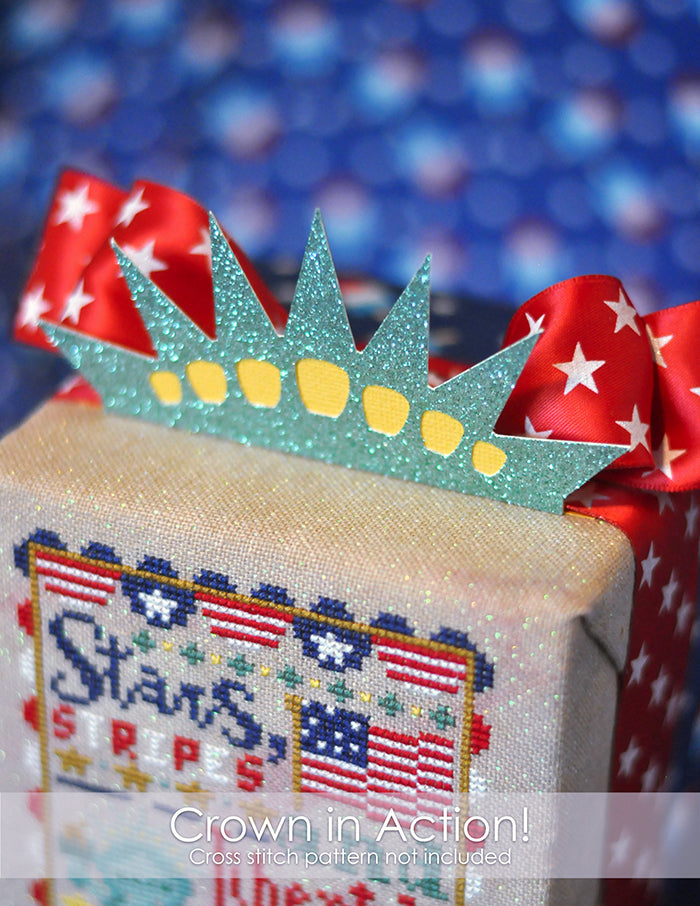 Liberty's Lights PNG cut file of a crown. The paper crown is placed on top of a finished cross stitch cube.
