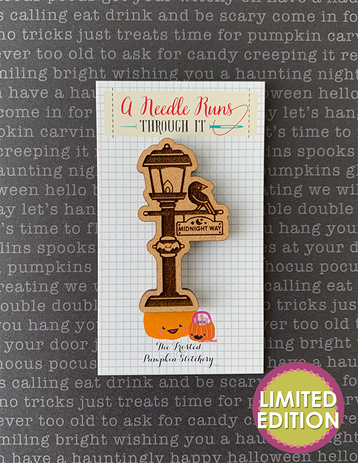 Image of wooden needleminder in the shape of a raven sitting on a lamp post. Lamp post sign reads "Midnight Way."