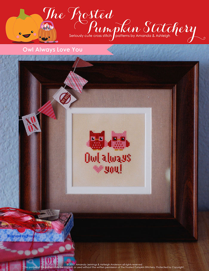 Owl Always Love You counted cross stitch pattern. Two little owls, one pink and one red are sitting next to each other. Text reads "Owl Always Love You". Owls are stitched on perforated paper and in a brown frame.