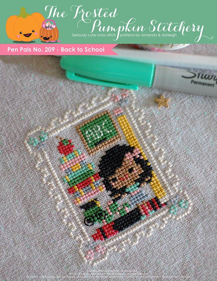 Pen Pals No 209 Back to School counted cross stitch pattern. A girl with brown skin and dark hair stands with a caterpillar wearing glasses and a chalk board that says ABC. 