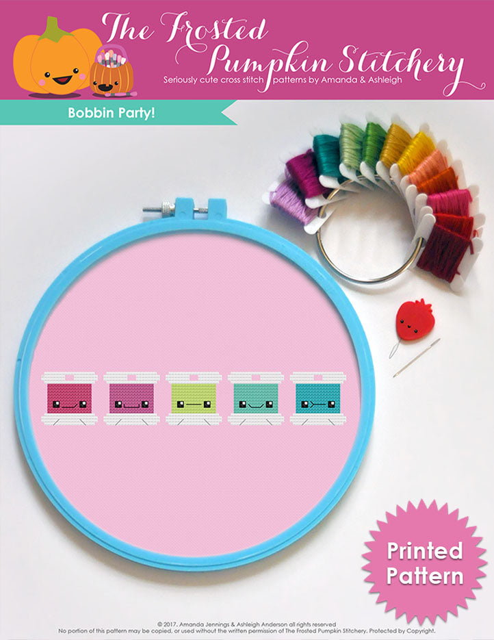 Bobbin Party Cross Stitch Pattern. Text reads "Printed Pattern". A blue embroidery hoop with pink fabric and a rainbow of embroidery floss bobbins with different faces.