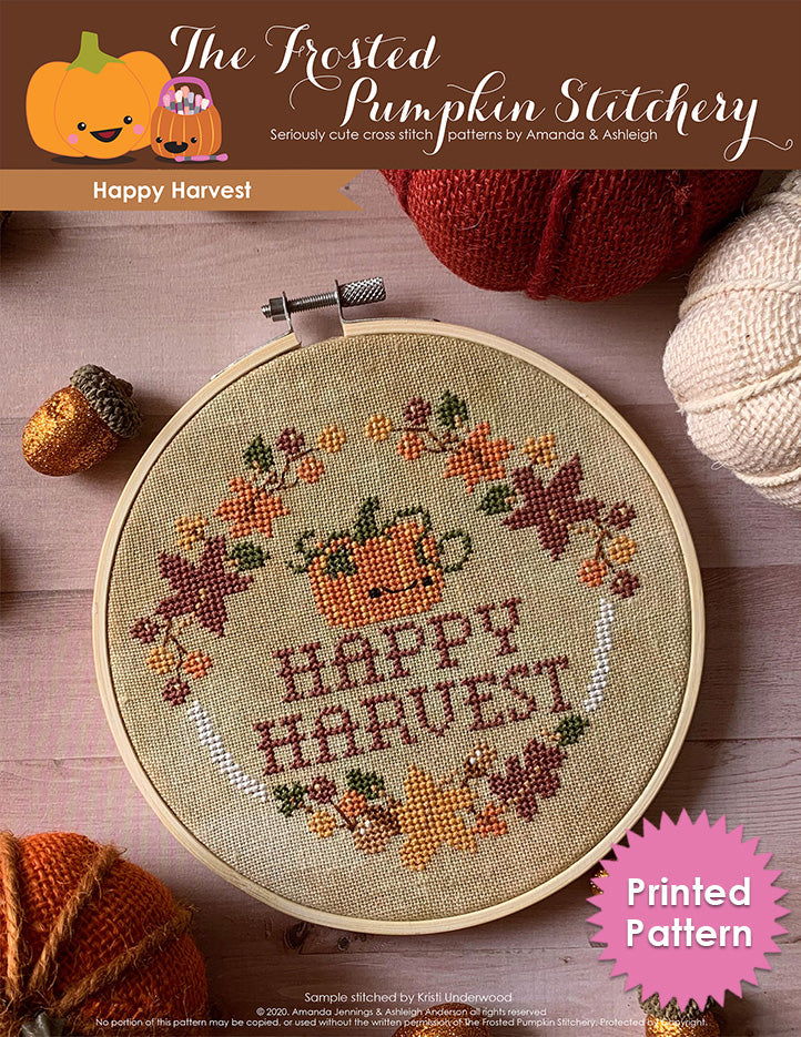 Happy Harvest cross stitch cover image. Picture of a pumpkin surrounded by autumn leaves, acorns, berries and the words "Happy Harvest." Printed Pattern.