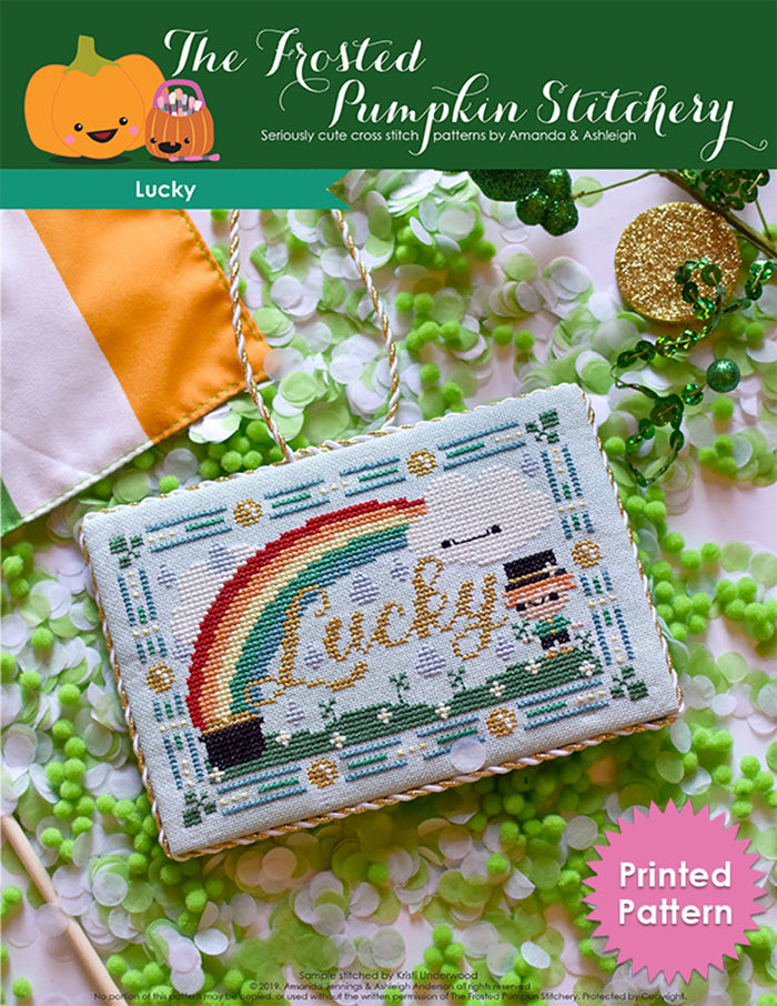 Lucky counted cross stitch pattern. Finished as a flat fold with gold and white trim. Pattern is a rainbow with a pot of gold, a cloud with a face, a leprechaun and grass. Printed Pattern
