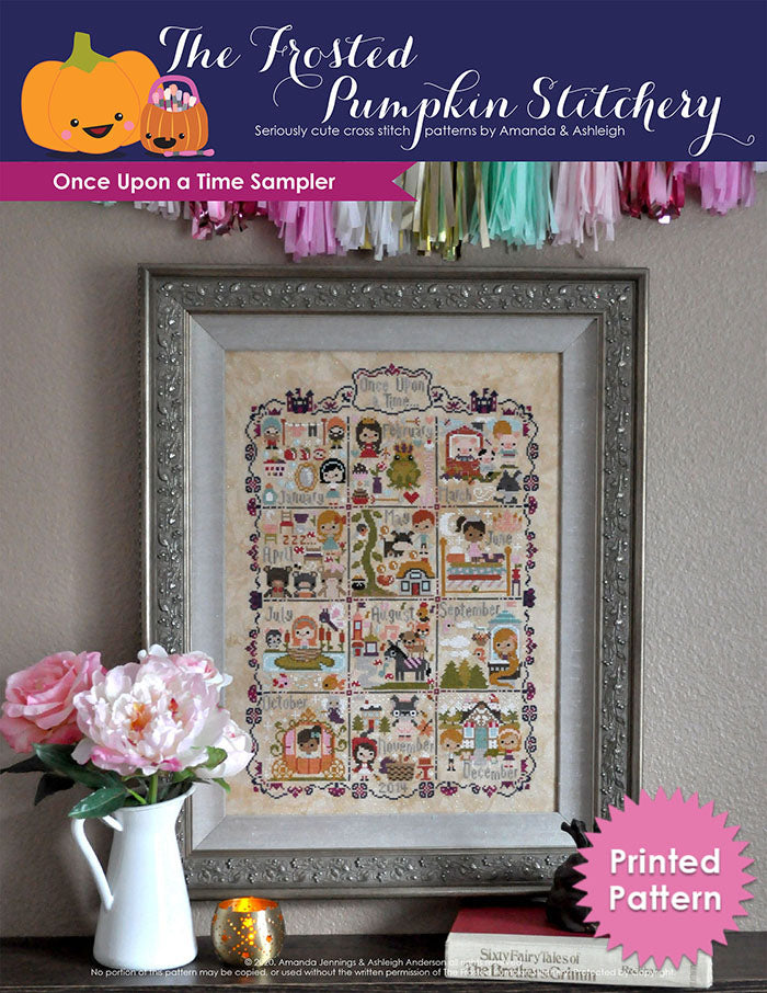 Once Upon a Time Sampler counted cross stitch pattern. Stories include Snow White, Frog Prince, Three Little Pigs and more. Framed piece is against a neutral wall with peonies in a vase in front of it. Printed Pattern.