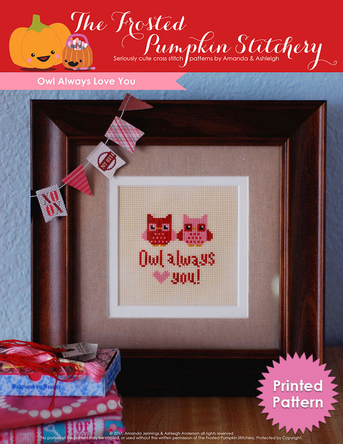Owl Always Love You counted cross stitch pattern. Two little owls, one pink and one red are sitting next to each other. Text reads "Owl Always Love You". Owls are stitched on perforated paper and in a brown frame. Printed Pattern.