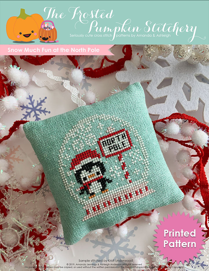 Snow Much Fun at the North Pole counted cross stitch pattern. A penguin inside a snow globe with snowflakes next to a sign that says "north pole". Printed Pattern.