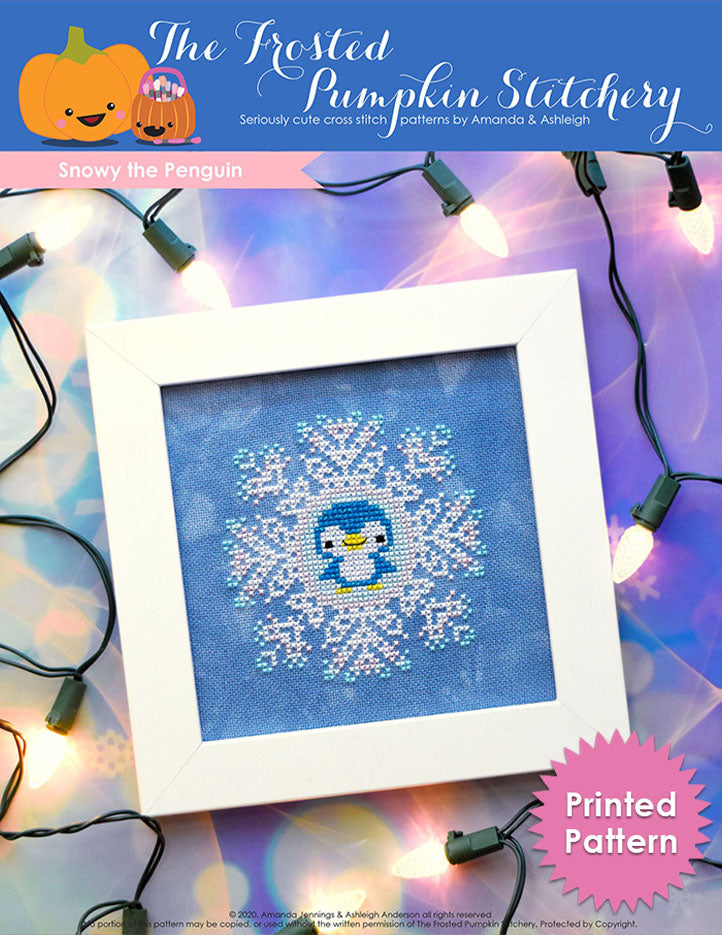 Image of Snowy the Penguin counted cross stitch pattern featuring a sparkly blue penguin in the center of a snowflake and framed in a simple white frame. Printed Pattern.