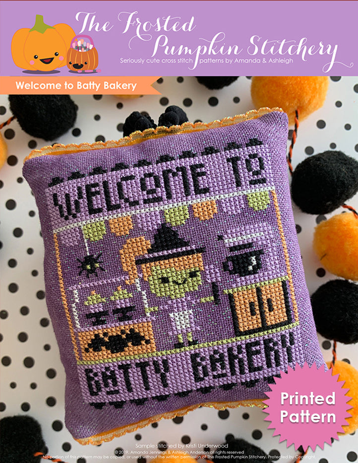 Welcome to Batty Bakery Halloween counted cross stitch pattern. A green skinned purple haired witch stands in front of a mixer holding a spatula. Printed Pattern.