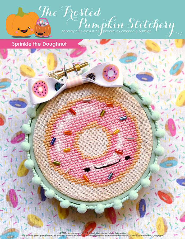 Sprinkle the Doughnut counted cross stitch pattern. Sprinkle is a doughnut with pink frosting and bead sprinkles. He's finished in a mint green embroidery hoop.