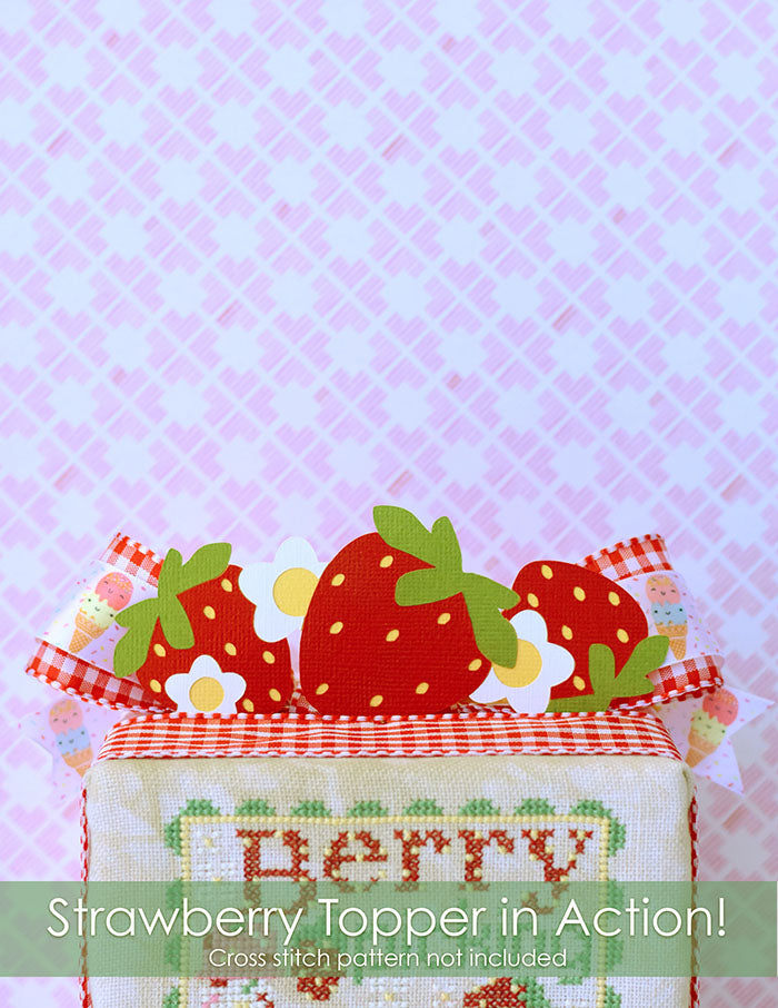 Strawberry topper in action. Paper strawberries and white strawberry flowers on top of a counted cross stitch project.
