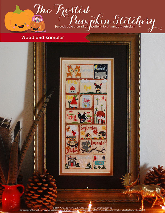 Woodland Sampler counted cross stitch pattern. Twelve animals with monthly calendar names in a brown frame with gold edges. Animals include deer, raccoon, skunk, fox, hedgehogs and squirrels.