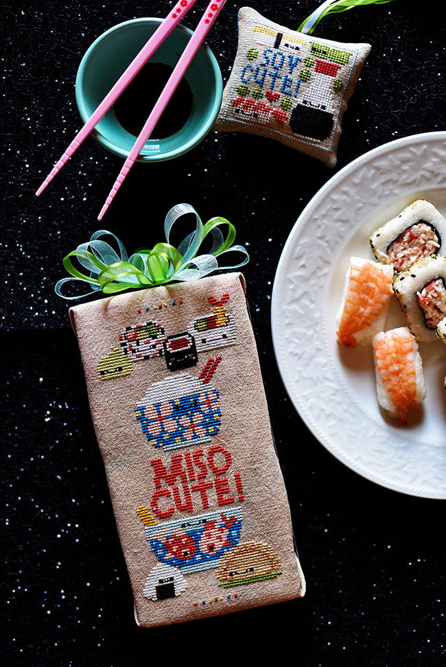 Miso cute and soy cute counted cross stitch projects. On a sparkly black background with a plate of sushi.