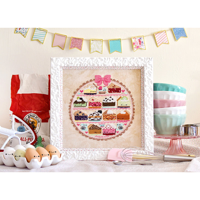 Sweet as Pie counted cross stitch pattern. Bunting in the background with bowls stacked on a cake tray and a bag of flour.